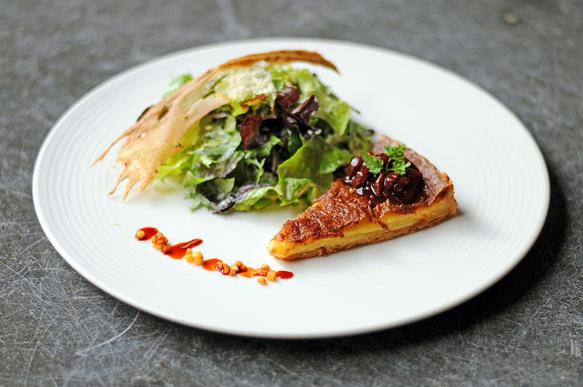 Handkäsekuchen Ein Stück Handkäsekuchen garniert mit einem Salatbuquet.